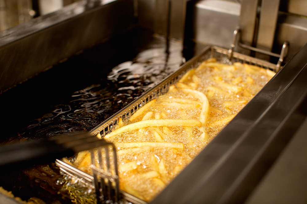 Pommes frites werden in einer Fritteuse in heißem Frittierfett zubereitet